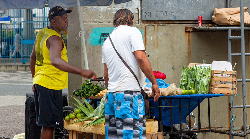 #PraCegoVer foto de vendedor na sua barraca de verduras atendendo um comprador