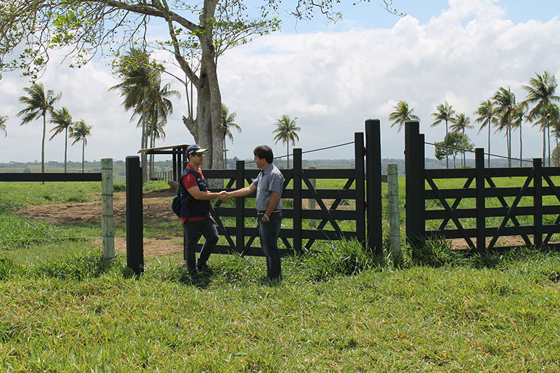 #pracegover Proprietário da fazenda recebe o recenseador do IBGE com um aperto de mãos